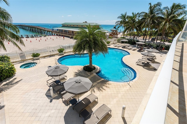 view of pool featuring a water view and a patio