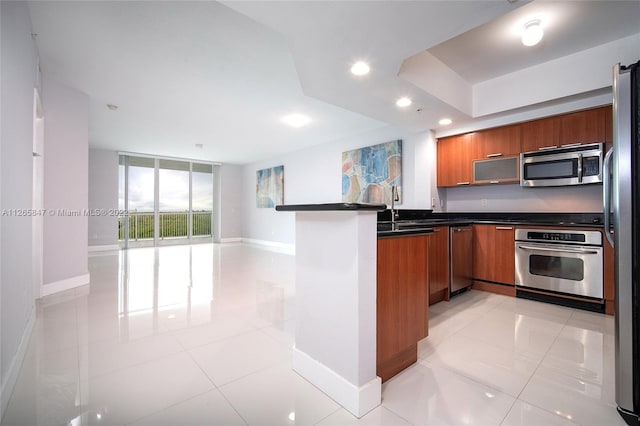 kitchen with floor to ceiling windows, kitchen peninsula, light tile floors, and appliances with stainless steel finishes