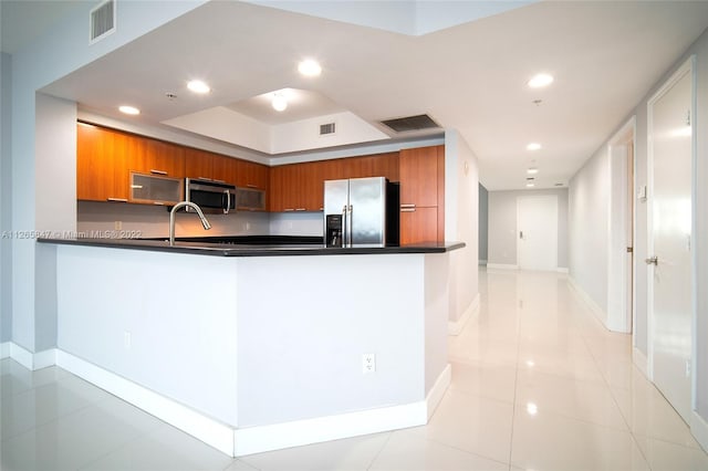 kitchen with light tile floors, appliances with stainless steel finishes, and kitchen peninsula