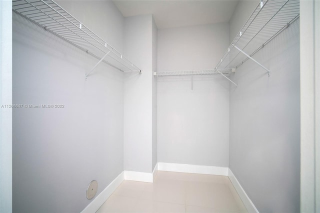 walk in closet with light tile floors