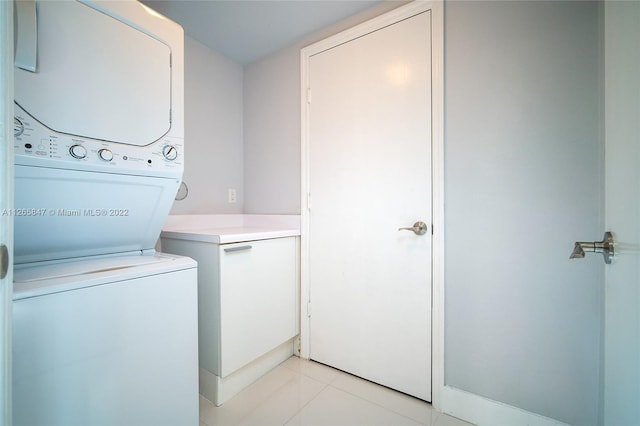 washroom featuring stacked washing maching and dryer and light tile floors