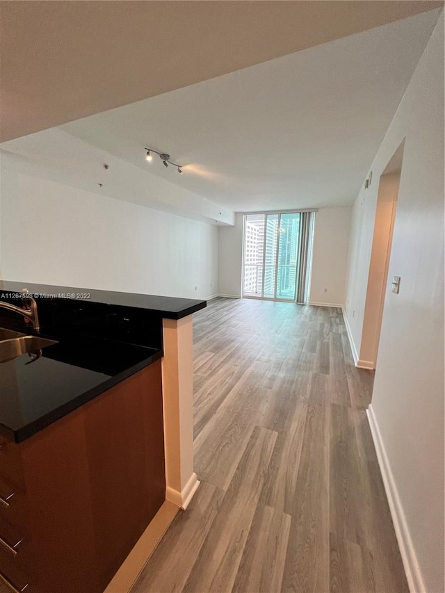 kitchen with floor to ceiling windows, rail lighting, sink, and light wood-type flooring