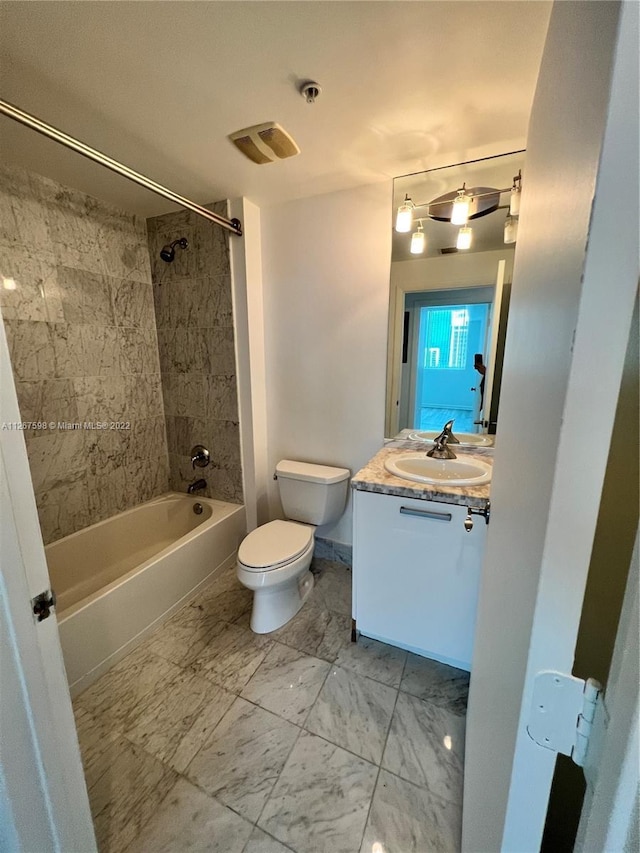 full bathroom featuring oversized vanity, tiled shower / bath combo, toilet, and tile floors