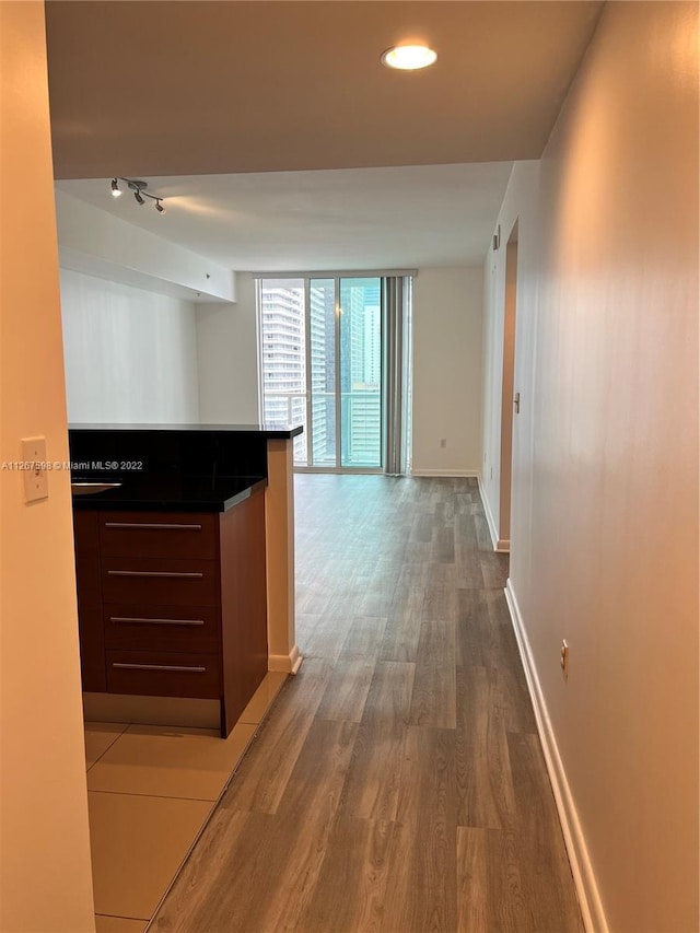 corridor featuring dark hardwood / wood-style floors, rail lighting, and expansive windows