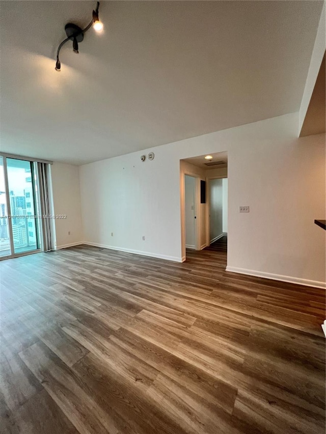 empty room with dark hardwood / wood-style floors and rail lighting