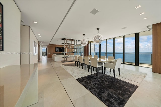 dining area with a chandelier, a water view, light tile floors, and a wall of windows