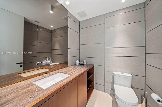 bathroom with tile walls, oversized vanity, and toilet