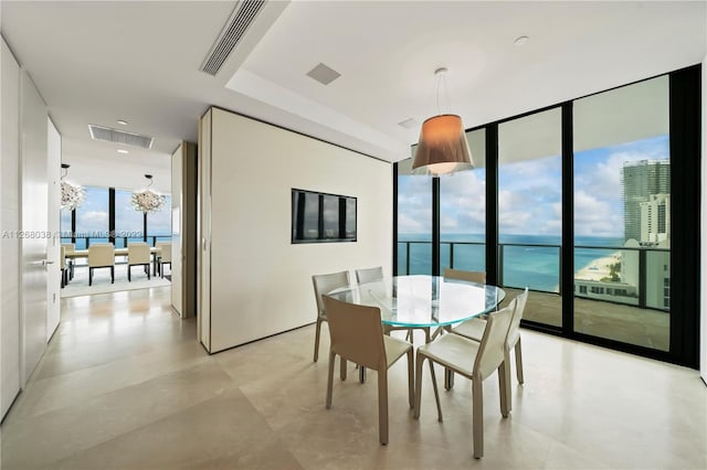 tiled dining space featuring an inviting chandelier, a wall of windows, and a water view