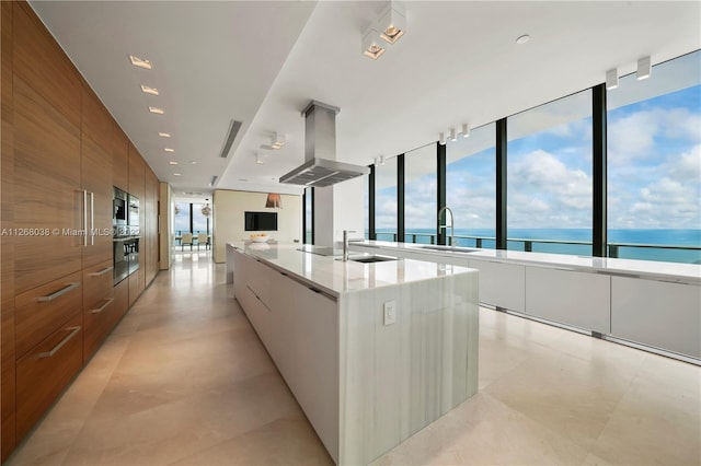 kitchen featuring white cabinetry, a kitchen island with sink, sink, light tile floors, and island range hood