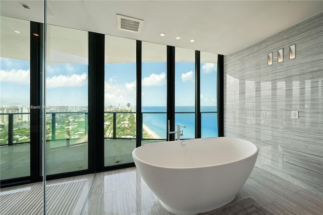 bathroom featuring tile flooring, a wall of windows, a wealth of natural light, and a water view