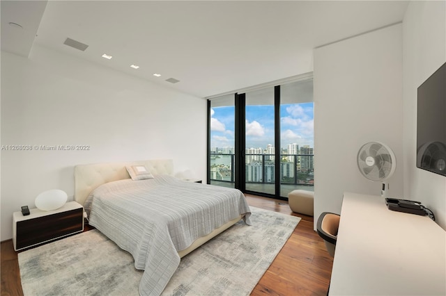 bedroom with expansive windows, access to exterior, and light hardwood / wood-style flooring