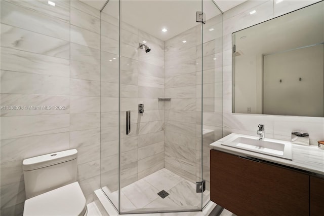 bathroom with tile walls, oversized vanity, toilet, and a shower with shower door