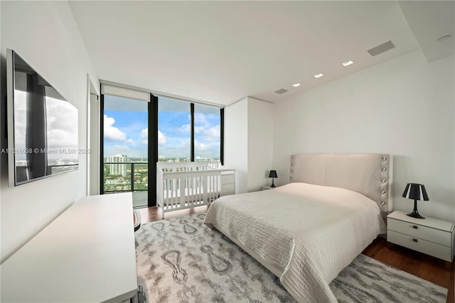 bedroom with access to outside, dark hardwood / wood-style floors, and a wall of windows