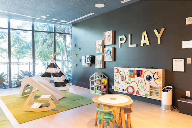 game room featuring floor to ceiling windows and light hardwood / wood-style floors