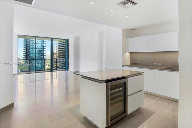 kitchen featuring visible vents, modern cabinets, wine cooler, a center island, and white cabinetry