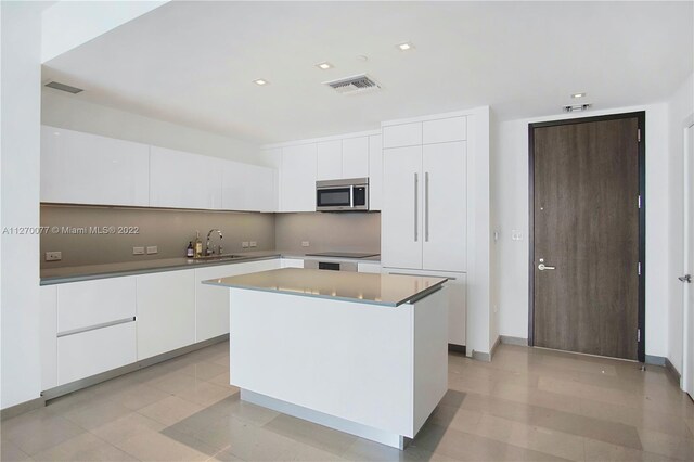 kitchen with stainless steel microwave, modern cabinets, white cabinetry, and a center island