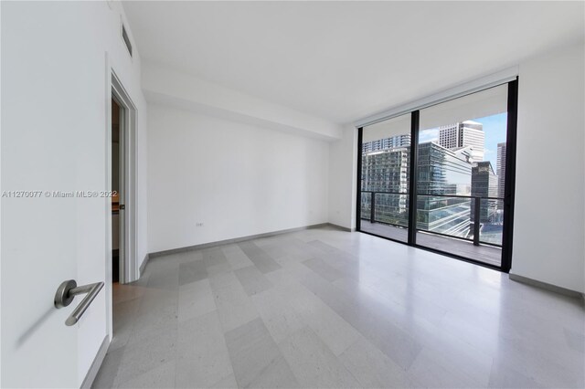 empty room featuring baseboards, light floors, visible vents, and floor to ceiling windows