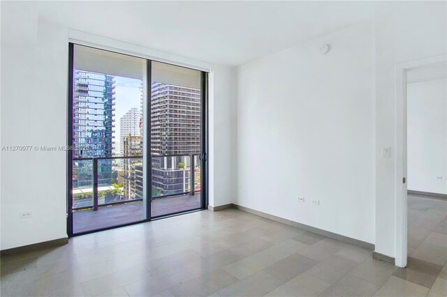 empty room with a view of city, a wall of windows, and baseboards