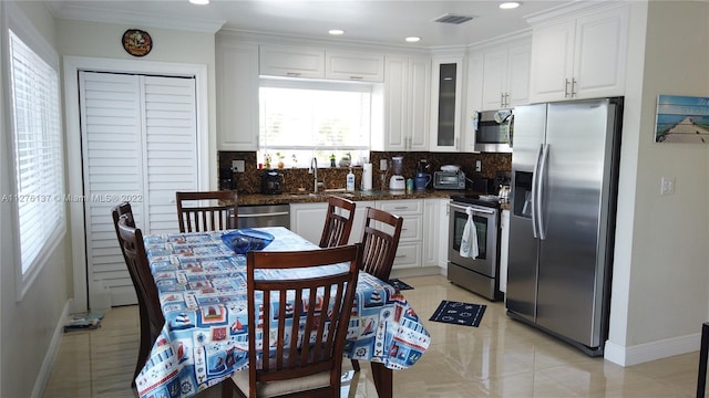 kitchen featuring white cabinetry, light tile flooring, sink, stainless steel appliances, and tasteful backsplash