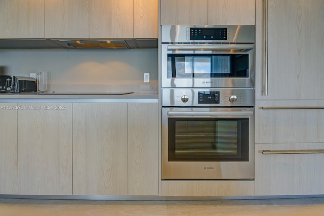 kitchen with light brown cabinets, stainless steel double oven, and fume extractor