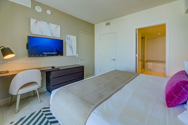 bedroom featuring connected bathroom and light hardwood / wood-style flooring