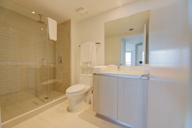 bathroom with a shower with door, tile floors, oversized vanity, and toilet