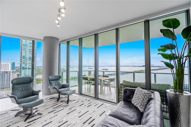 sunroom / solarium featuring rail lighting and a water view