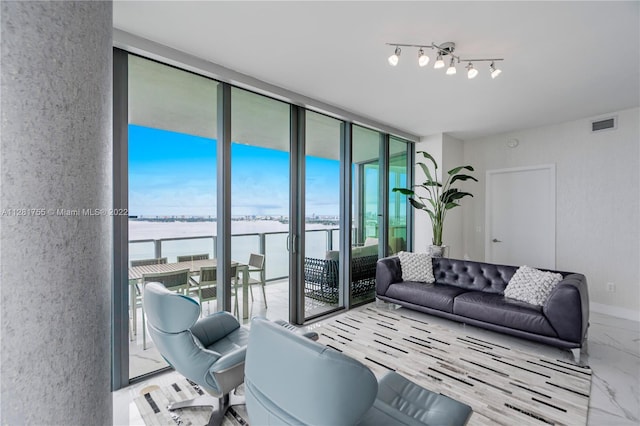 living room with a water view, a wall of windows, light hardwood / wood-style flooring, and track lighting