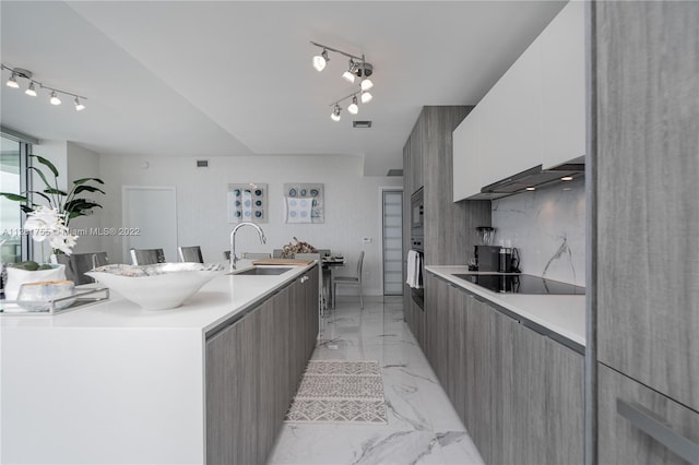 kitchen featuring rail lighting, white cabinets, black electric stovetop, and sink