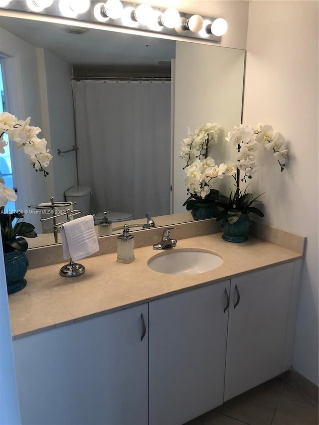 bathroom featuring toilet, vanity, and tile flooring