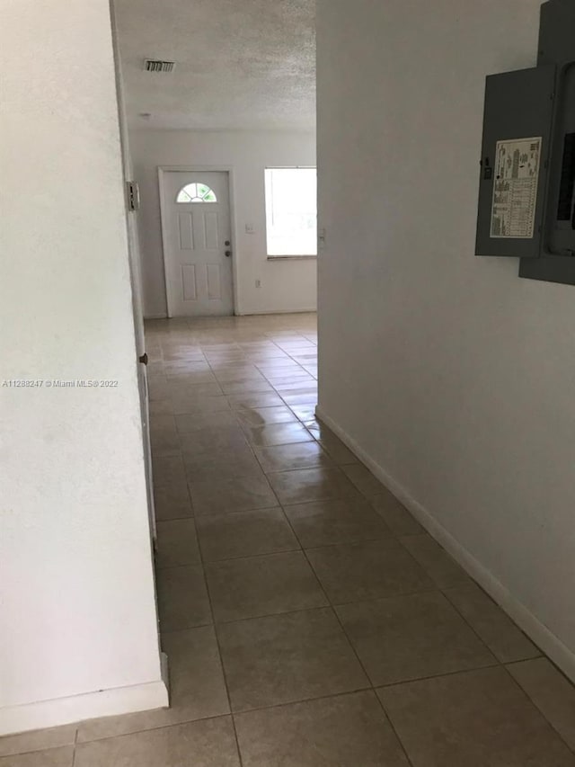 hall featuring tile patterned floors, a textured ceiling, and electric panel