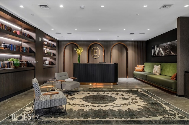 interior space with built in shelves, wood walls, and concrete flooring