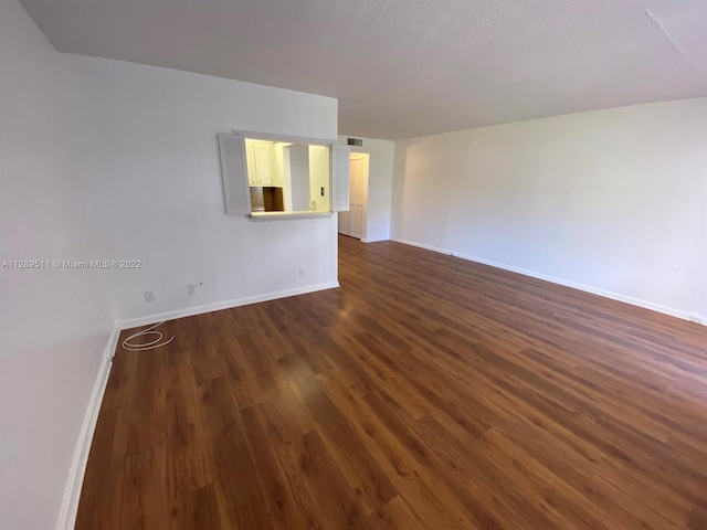 empty room with a textured ceiling and dark wood-type flooring