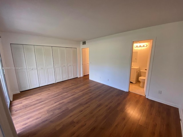 unfurnished bedroom featuring ensuite bath and dark hardwood / wood-style flooring