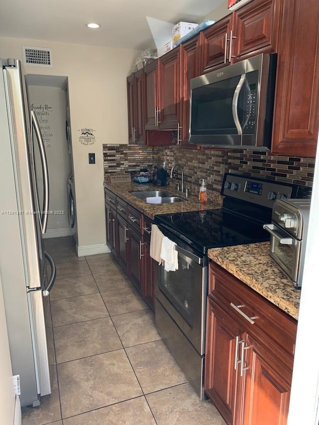 kitchen with light stone counters, tasteful backsplash, stainless steel appliances, and sink