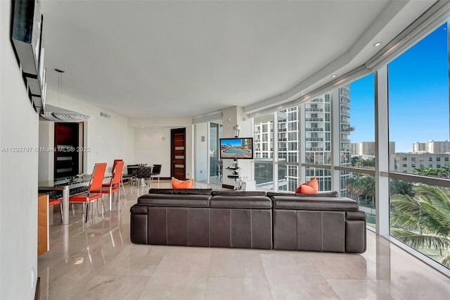 living room with light tile flooring, plenty of natural light, and a wall of windows