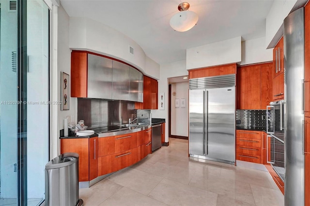 kitchen with stainless steel counters, backsplash, appliances with stainless steel finishes, sink, and light tile floors