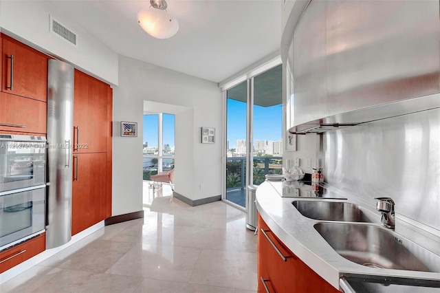 kitchen featuring a wall of windows, sink, and light tile floors