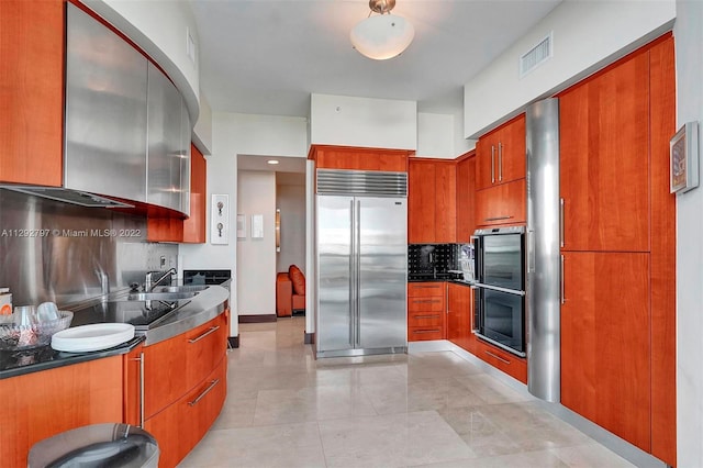 kitchen with light tile floors, black electric cooktop, tasteful backsplash, built in fridge, and sink