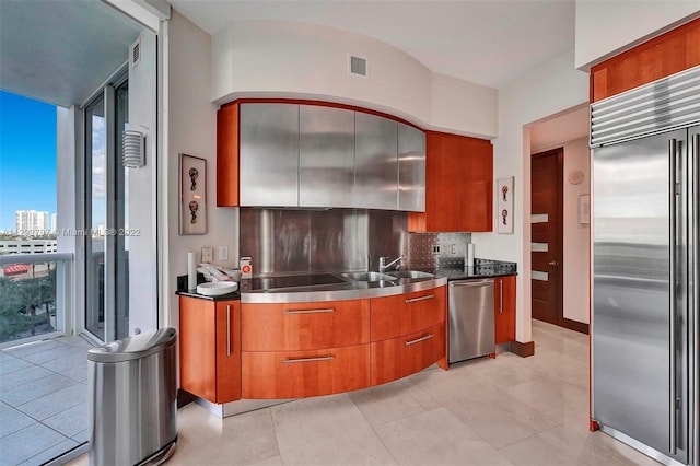 kitchen featuring tasteful backsplash, appliances with stainless steel finishes, light tile floors, and dark stone countertops