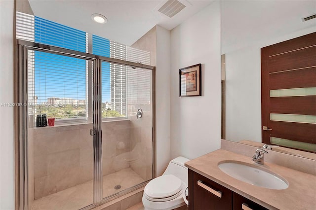 bathroom with toilet, vanity, and a shower with shower door