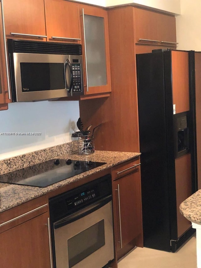 kitchen with light stone counters and black appliances