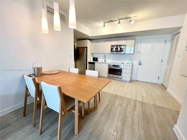 dining area with sink, track lighting, and light wood-type flooring