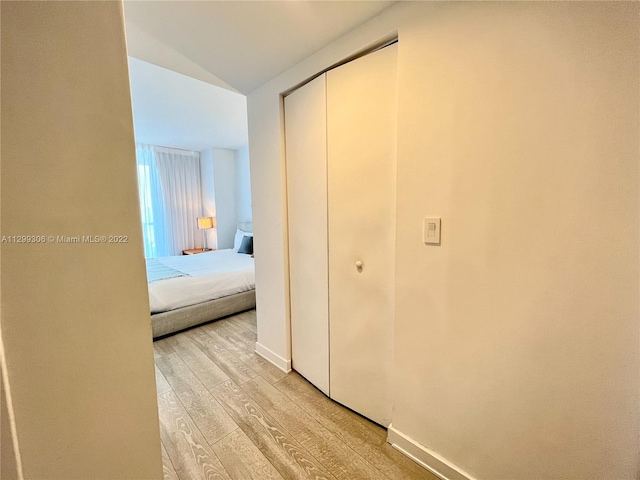 hallway featuring lofted ceiling and light hardwood / wood-style flooring