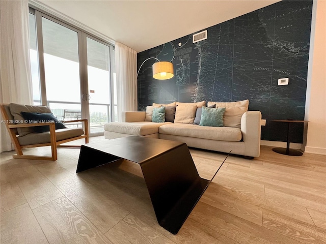 living room featuring a wall of windows, french doors, and light wood-type flooring