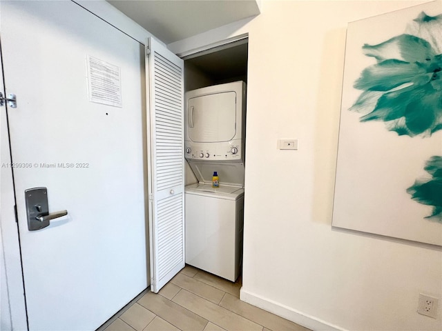 laundry area featuring stacked washer and clothes dryer and light tile floors