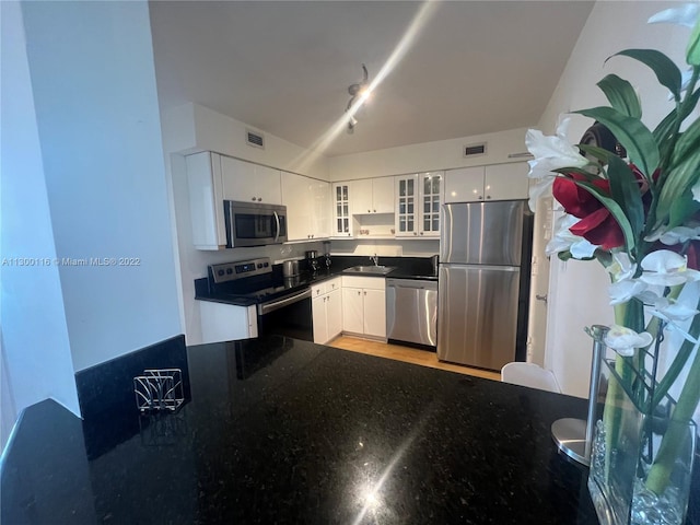 kitchen with light wood-type flooring, rail lighting, stainless steel appliances, and white cabinetry