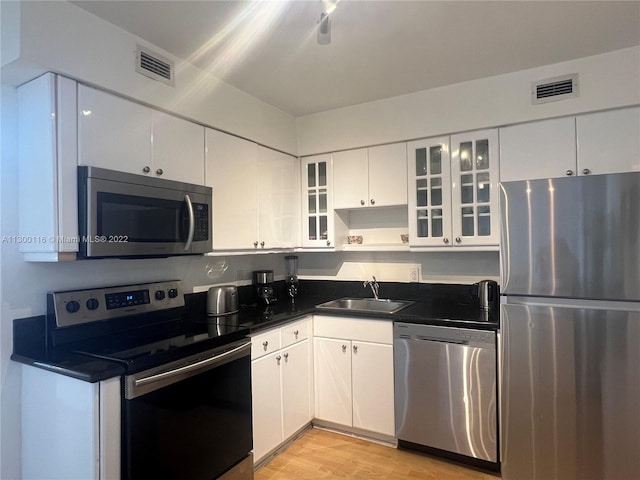 kitchen featuring stainless steel appliances, light hardwood / wood-style flooring, white cabinetry, and sink