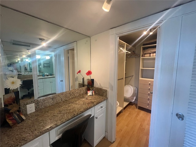 interior space with dark stone countertops, white cabinets, and light hardwood / wood-style flooring