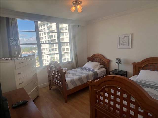 bedroom with crown molding and light wood-type flooring